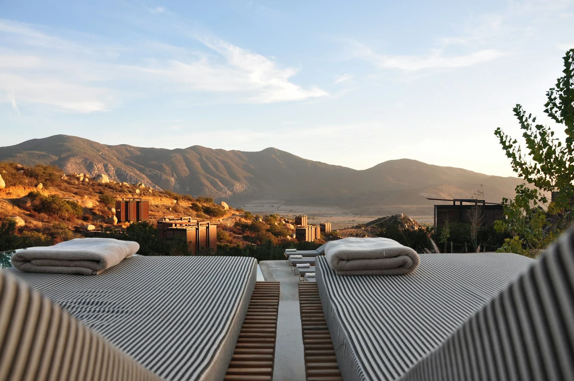 Empty daybeds overlooking a hazy valley at dusk